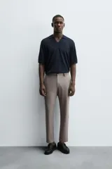 Pantalón chino de corte slim fit, confeccionado en tejido elástico. Presenta bolsillos frontales, bolsillos traseros de vivo con botón y cierre frontal con cremallera y botón.