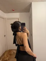 Top lencero negro de satén con cuello halter y detalles de encaje en los bordes.
