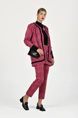 Conjunto de dos piezas compuesto por un saco tipo blazer de corte recto con cierre frontal de botones y ribetes negros en contraste, y un pantalón de vestir de corte recto a juego. Ambas prendas presentan un diseño de tejido texturizado en tonos rosa.