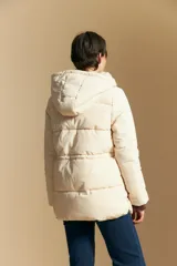 Campera acolchada de nylon en color crema, con capucha ajustable, cierre frontal con botones y cordón de ajuste en la cintura.