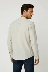 Camisa de manga larga con cuello mao y cierre frontal de botones. Presenta un diseño de rayas verticales en tonos beige y blanco.