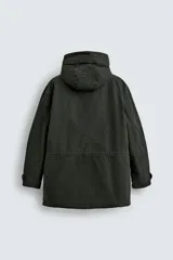 Parka color verde militar de corte relaxed fit, confeccionada en tejido de algodón con interior acolchado. Cuenta con cuello subido, capucha ajustable con cordón, cierre frontal de cremallera oculta por solapa con botones a presión y amplios bolsillos frontales de plastrón con solapa.