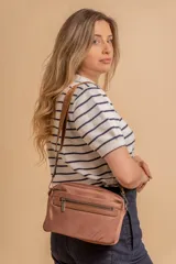 Bandolera de diseño moderno y funcional, confeccionada en nylon color marrón claro. Cuenta con múltiples compartimentos con cierre metálico, herrajes plateados y una correa ancha ajustable con detalle de marca.