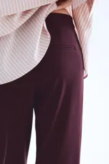 Pantalón de vestir color borgoña oscuro, de corte bootcut con raya marcada en el frente y la espalda. Presenta pretina prolongada con cierre oculto y bolsillos al bies y ribeteados en la parte trasera.