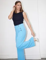 Pantalón naranja de crepe elastizado, corte recto, con bolsillos delanteros y apliques de botones metálicos.