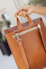 Mochila marrón de cuero con textura tipo piel de cocodrilo, con cierre superior y bolsillo frontal con cierre.