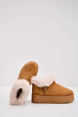 Bota corta tipo moon boot color camel, con plataforma plana y detalle de piel sintética en el borde superior. Incluye una tira decorativa con hebilla metálica en el lateral.