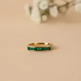 Anillo de oro amarillo 18k con diseño de media alianza engastado con esmeraldas en talla cuadrada.