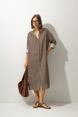 Vestido camisero midi de corte recto y holgado, con estampado de rayas verticales en tonos tierra, cuello camisero, cierre frontal de botones y mangas tres cuartos con puños vueltos.