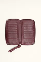 Billetera rectangular de cuero con textura de reptil, cierre perimetral y correa de muñeca lateral. Presenta un pequeño aplique metálico circular en el centro.