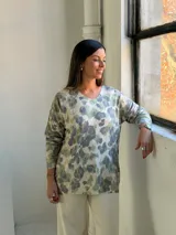 Sweater de punto con estampado animal print en tonos verde claro y gris sobre fondo beige, de cuello redondo y manga larga.