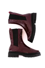 Bota tipo chelsea de cuero acharolado negro, con elásticos laterales y suela track dentada.