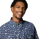 Camisa de manga corta Columbia, diseñada para pesca, con estampado de peces y elementos náuticos. Presenta cuello abotonado, cierre frontal con botones, múltiples bolsillos en el pecho y ventilación trasera forrada en malla.