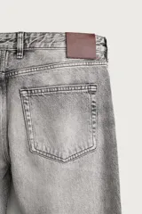 Jeans flare fit de denim de algodón en color gris con efecto lavado. Presentan diseño de cinco bolsillos, tiro medio y cierre frontal con cremallera y botón.