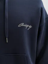 Buzo con capucha y bolsillo canguro, de calce holgado y manga larga. Confeccionado en tejido loopback, presenta estampa frontal y trasera con acabado pigmentado.