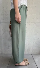 Pantalón tipo babucha de color verde militar, con cintura elástica fruncida y cordón ajustable. Cuenta con diseño amplio y puños elásticos en los tobillos.