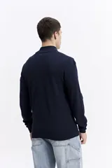 Buzo de punto con medio cierre frontal, cuello elevado y puños acanalados. Presenta un pequeño logo bordado en el pecho.