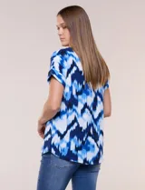 Blusa de silueta holgada y recta, confeccionada en crepe de poliéster con estampado animal print. Presenta escote redondo clásico, mangas cortas de hombro caído con puño doblado y ruedo ligeramente curvo.