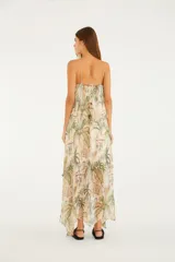 Vestido largo de poliéster con forro de viscosa, de corte amplio y silueta fluida en capas, con estampado tropical de palmeras en tonos verdes y tostados sobre fondo beige, escote en V y tirantes finos.