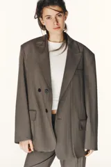 Blazer oversize de Zara con diseño a rayas verticales, cuello con solapa de muesca y hombreras. Presenta un cierre frontal cruzado con doble botonadura, bolsillos delanteros con solapa y un bolsillo de vivo en el pecho. Incluye forro interior a tono.