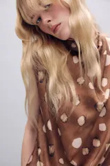 Top de cuello subido y diseño sin mangas, confeccionado en tejido satinado con estampado de manchas abstractas. Presenta drapeado frontal, bajo con elástico y cierre posterior con botones.