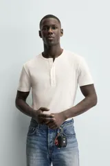 Camiseta blanca de manga corta con cuello redondo y tapeta de botones frontal (cuello panadero o henley).