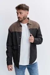 Cazadora acolchada de corte recto con diseño bicolor, presentando un panel superior en color marrón y cuerpo en color negro. Cuenta con cuello clásico, cierre frontal de botones y bolsillos delanteros con solapa.