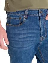 Jeans de corte slim en denim azul con efecto lavado, cierre de cremallera y botón, diseño de cinco bolsillos y detalles de la marca CAT.
