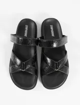 Sandalia plana marca Symphorine, color negro con acabado texturizado tipo charol. Presenta una tira superior ajustable y tiras cruzadas en el empeine.