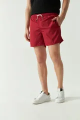 Short de baño liso con cintura elástica y cordón ajustable. Cuenta con dos bolsillos laterales, un bolsillo trasero y logo bordado. Confeccionado en tela ligera de secado rápido.