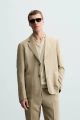 Blazer color beige de corte relaxed fit, confeccionada en tejido con viscosa. Tiene cuello con solapas de muesca, manga larga con puño abotonado, bolsillos frontales de plastrón, medio forro interior, aberturas en la espalda y cierre frontal con botones. Presenta un efecto lavado.