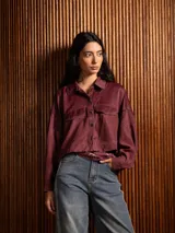 Campera corta de tela fina con diseño de paneles combinados, cuello camisero, cierre frontal con botones dorados y costuras a contratono.