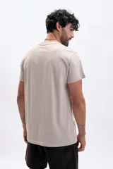 Remera de manga corta color taupe, con cuello redondo y estampado minimalista en el pecho que indica "EST. 1975 ST. ÉTIENNE FRANCE".