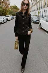 Pantalón flare de tiro bajo color marrón oscuro, con bolsillos delanteros y traseros, pierna entallada y bajo acampanado. Cierre frontal con cremallera y botón.