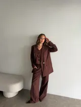 Conjunto de blazer y pantalón de lino gris con diseño de rayas diplomáticas. El blazer es de corte amplio con doble botonadura, y el pantalón es de corte recto y tiro alto.