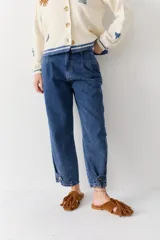 Jean de corte gaucho en color azul, con diseño de pinzas en la cintura, tiro medio y detalle de ajuste con botón en el ruedo.