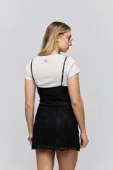 Vestido corto de encaje negro con breteles finos y corte ajustado al cuerpo.