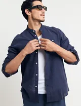 Camisa de manga larga con cuello mao, confeccionada en una mezcla de lino y algodón. Presenta cierre frontal con botones en tono natural y un bolsillo pequeño en el pecho.