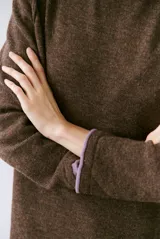 Buzo de tejido de punto color beige, con corte relajado, cuello redondo y mangas largas. Presenta detalles de terminaciones en color azul marino en los puños y en el ruedo inferior.