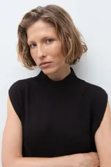 Vestido midi de tejido de punto, color negro, sin mangas, con cuello alto y tajo frontal en la falda.