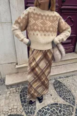 Jersey de punto con cuello redondo y manga larga, confeccionado con un tejido de efecto cepillado. Presenta un diseño jacquard con motivos geométricos en tonos beige y crema, con terminaciones en rib.