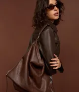 Bolso hobo grande de poliuretano color bordó, de diseño desestructurado con asas dobles y cierres laterales ajustables con tiradores. Cuenta con cierre superior y herrajes metálicos plateados.