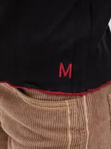 Polera de cuello alto confeccionada en tela rib color blanco, con mangas largas y hombreras. Presenta pespuntes en contraste en las terminaciones del cuello, hombros y puños.