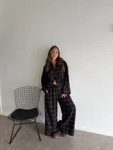 Pantalón de corte recto y holgado, confeccionado en tela de viyela con estampado de cuadros en tonos negro, gris y blanco. Presenta cintura elástica para mayor comodidad.