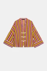 Camisa de rayas multicolor con predominio de verde, cuello redondo con escote en V y mangas anchas. Cuenta con cierre frontal mediante alamares de cordón blanco.