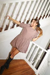 Vestido corto color malva/taupe, con mangas cortas abullonadas y corte fruncido en la cintura que genera una falda tipo globo (balloon).