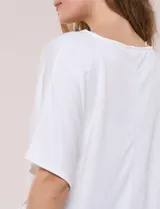 Remera blanca de manga corta, confeccionada en mezcla de modal, con diseño fluido y detalle de lazo ajustable en el lateral.