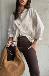 Camisa clásica a rayas beige y blancas, con cuello camisero, botones frontales y bordado decorativo en el pecho.