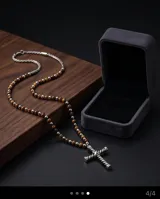 Collar de diseño artesanal compuesto por una cadena de cuentas alternadas de ónix y ojo de tigre, con un dije central de cruz de acero con diseño trenzado.
