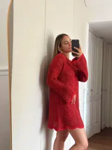 Vestido corto de tejido calado con patrón de ondas, confeccionado en algodón y lurex. Presenta mangas largas, cuello redondo y diseño holgado.